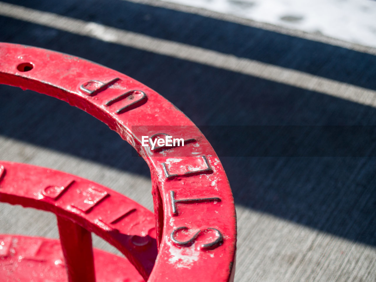 Close-up of text on red metal during sunny day