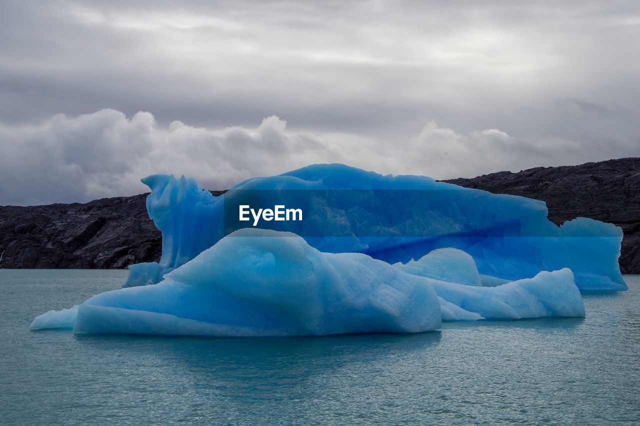 Scenic view of icebergs against cloudy sky