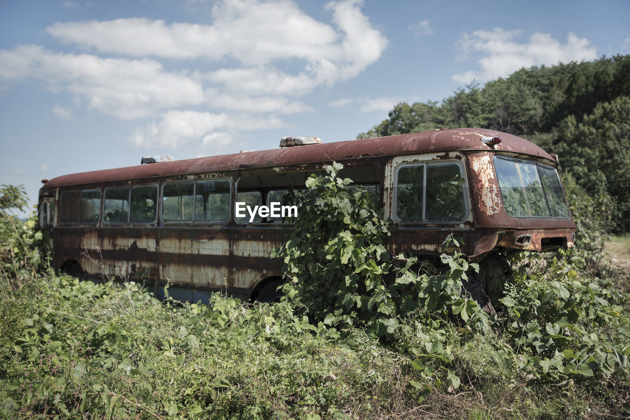 Abandoned bus on field against sky
