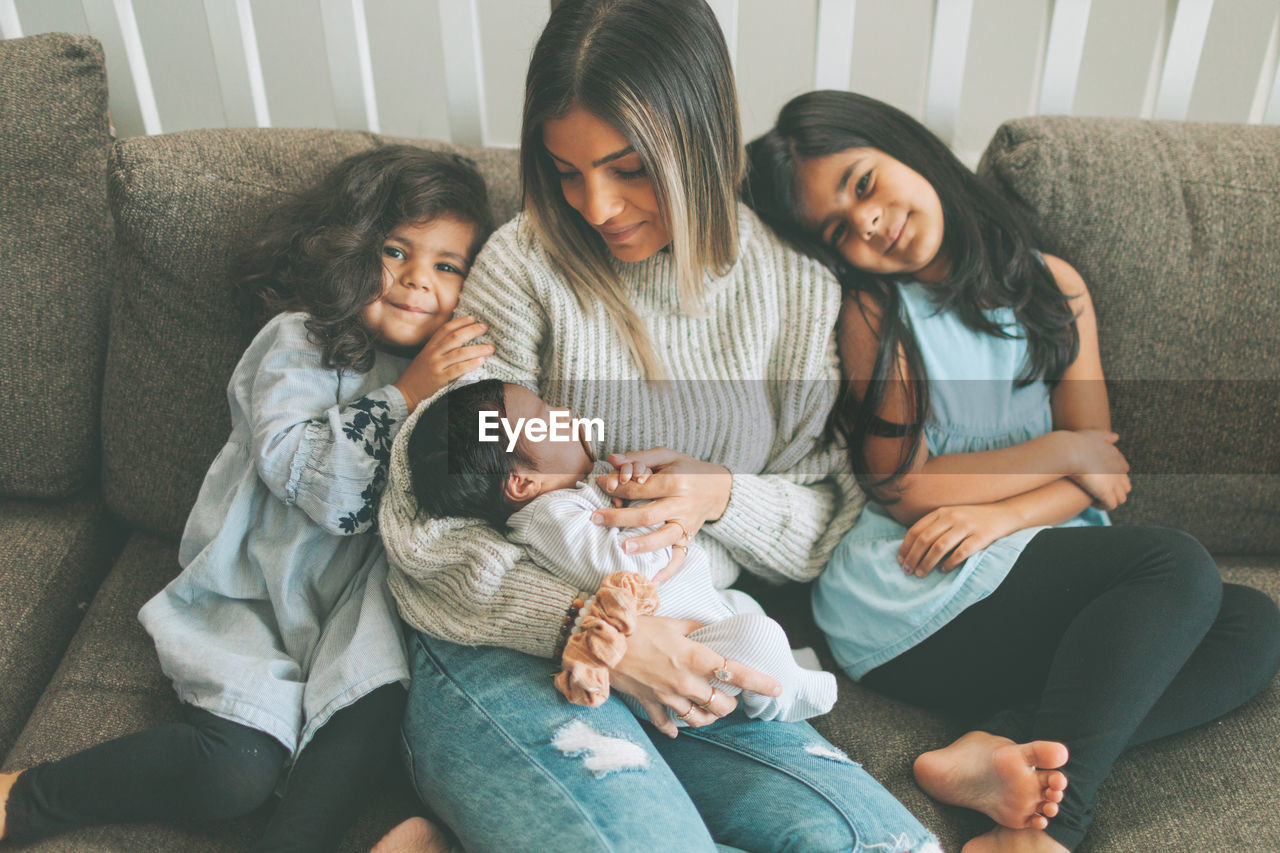 Mother with kids sitting on sofa at home