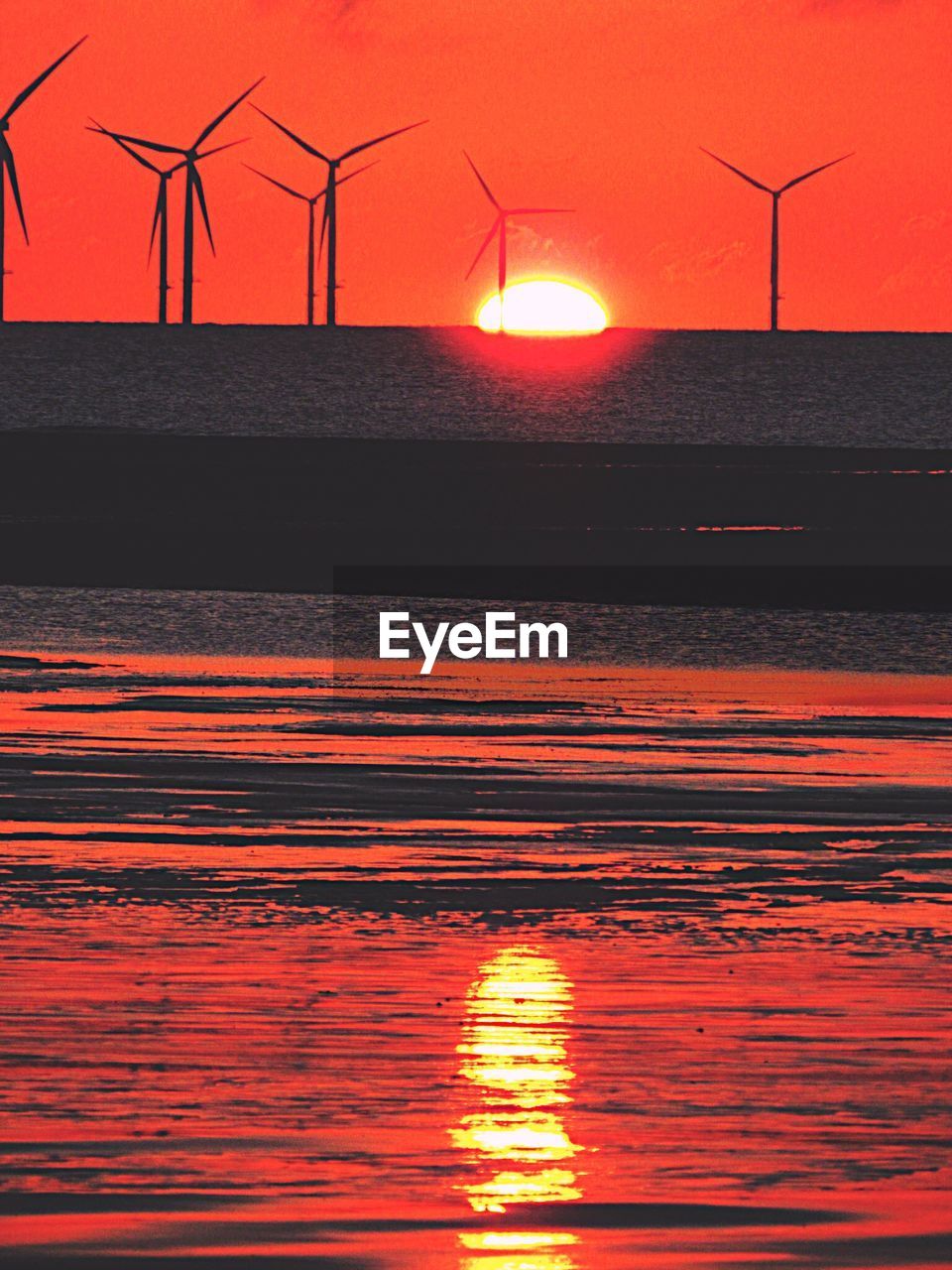 SILHOUETTE OF TRADITIONAL WINDMILL AGAINST ORANGE SKY