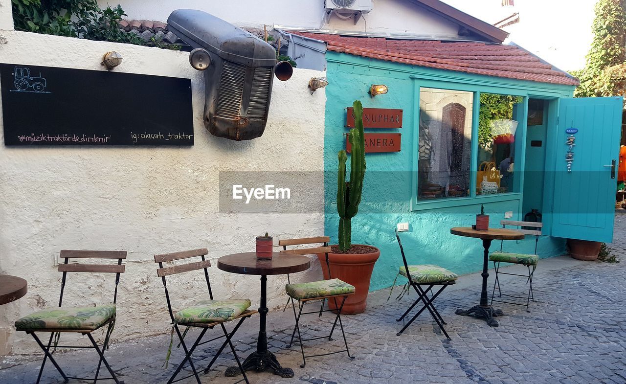 EMPTY CHAIRS AND TABLES AGAINST BUILDING