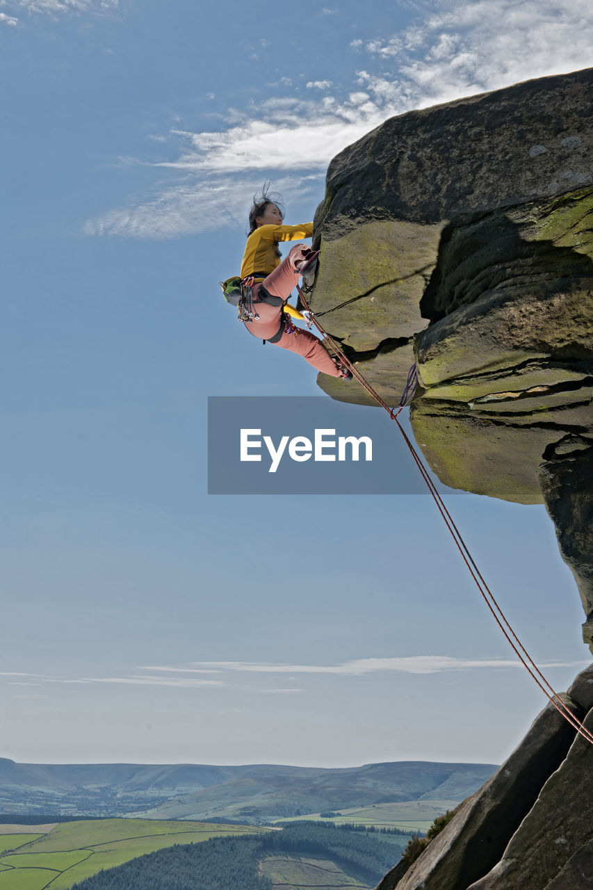Woman climbing at windgather rocks in the british peak district