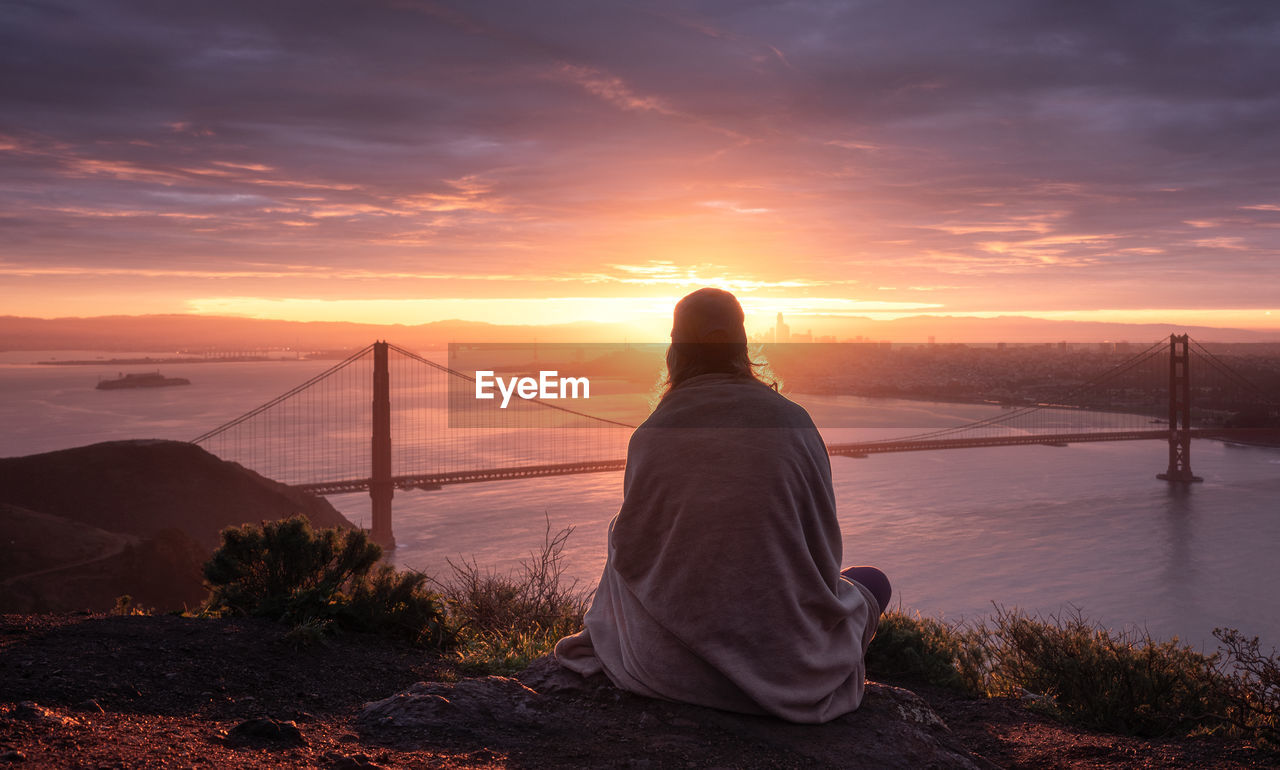 Rear view of woman looking at the golden gate bridge against sky during sunrise,  san francisco 