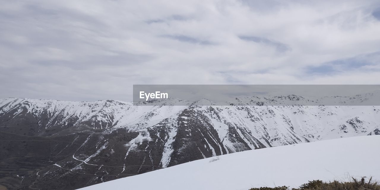 SNOW COVERED MOUNTAINS AGAINST SKY