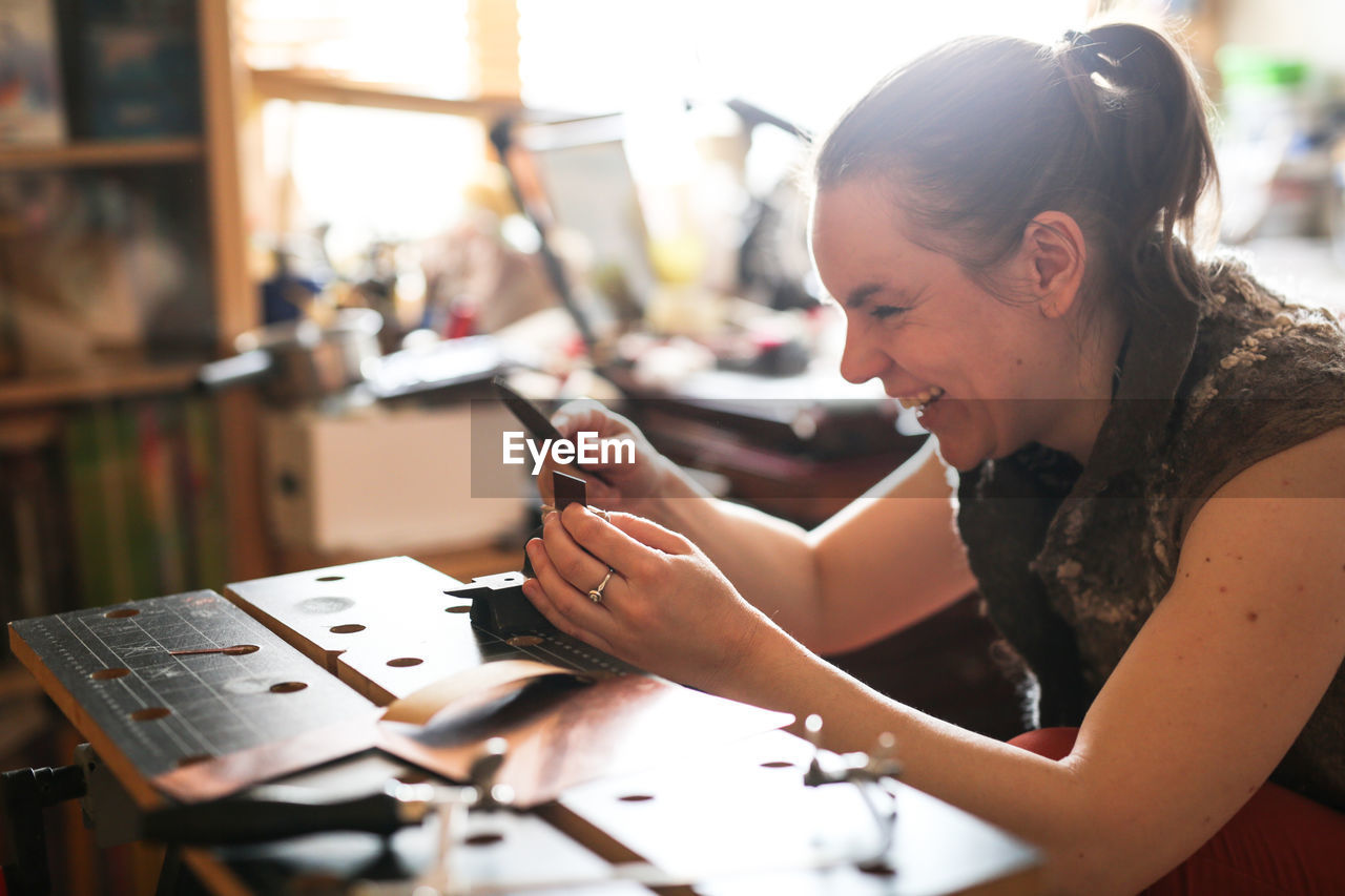 Girl master processes the metal copper plate on the workbench in the home workshop, soft focus 