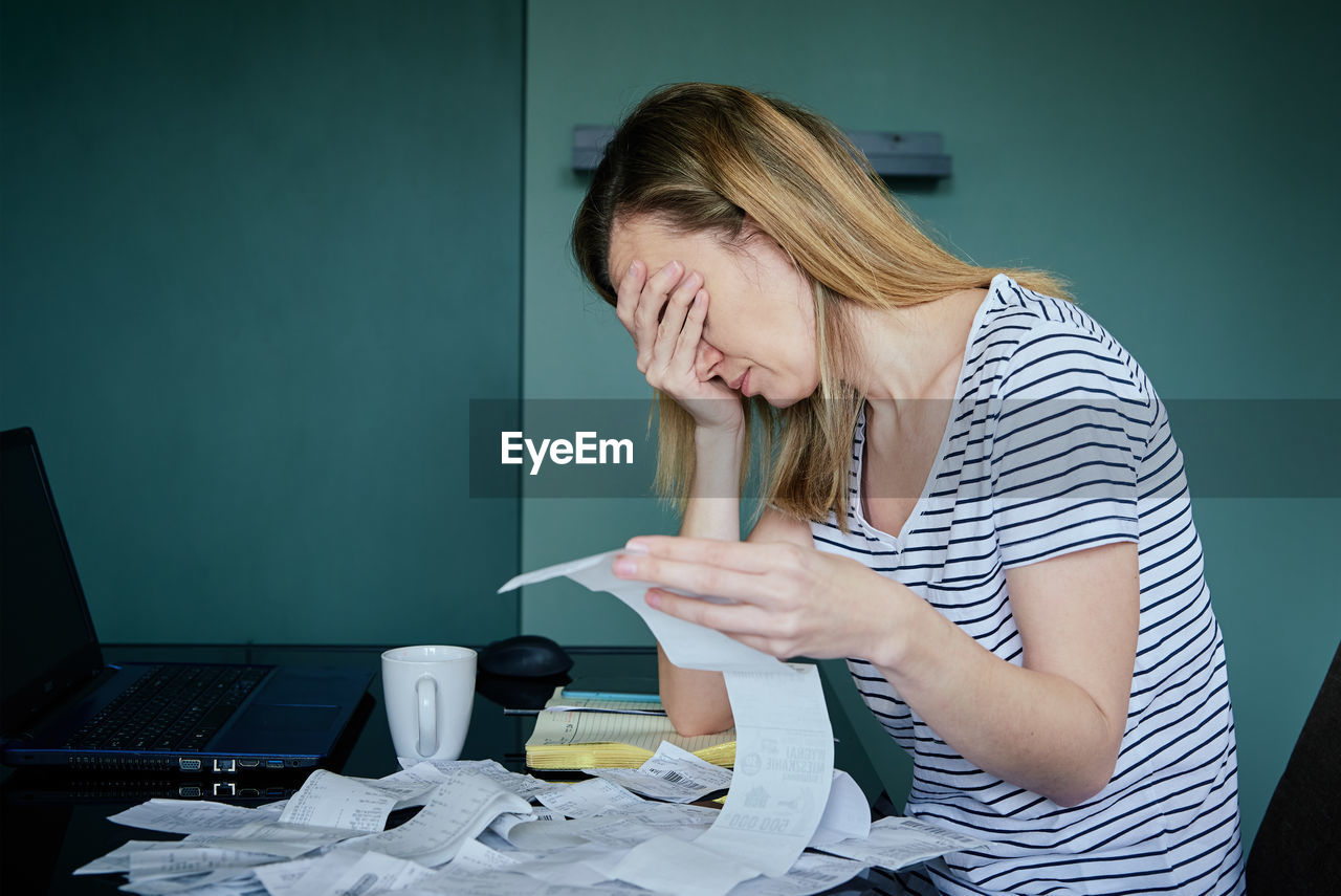 Woman calculating payment bill in kitchen