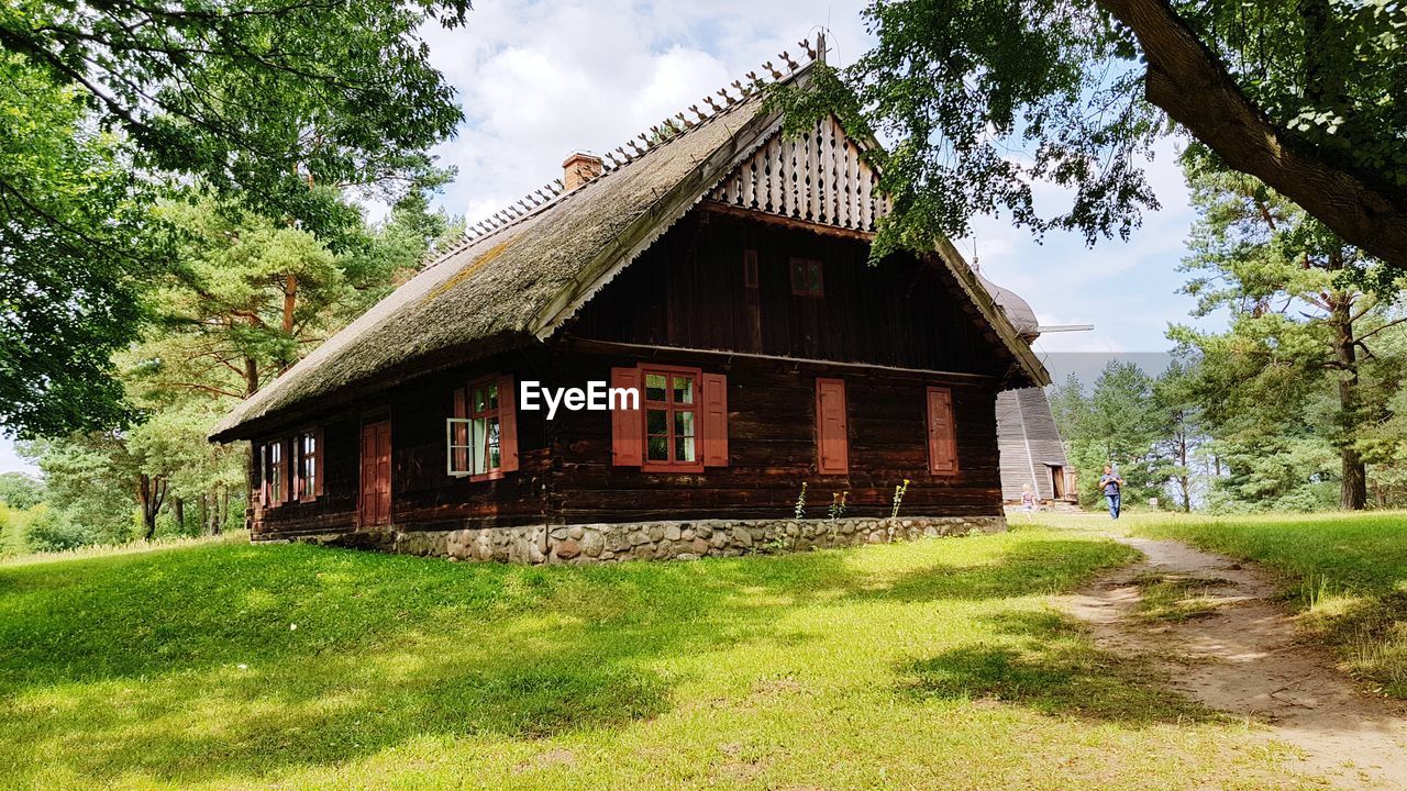 HOUSE ON FIELD AGAINST TREES AND HOUSES