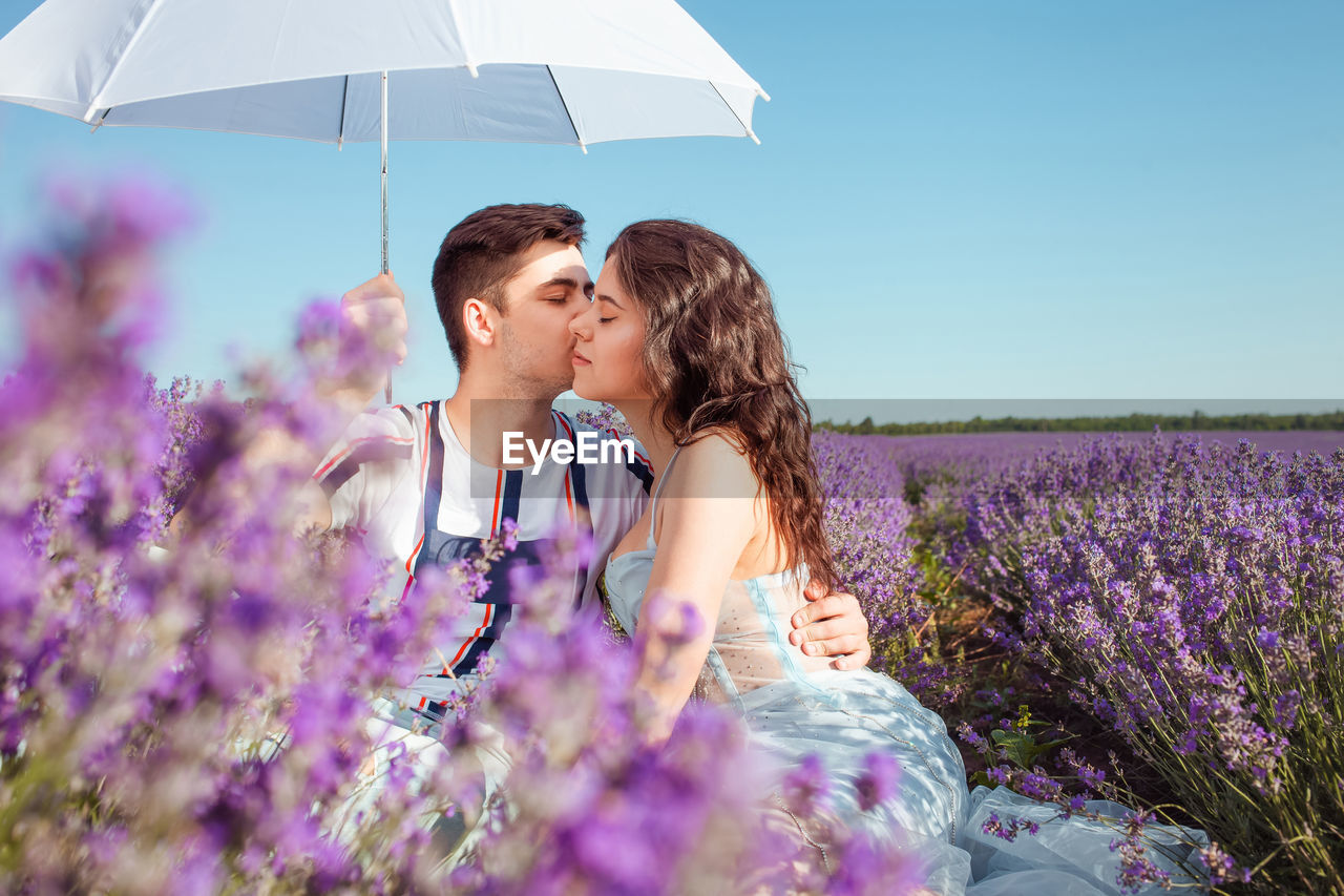 A couple in love under a white umbrella on a lavender field love
