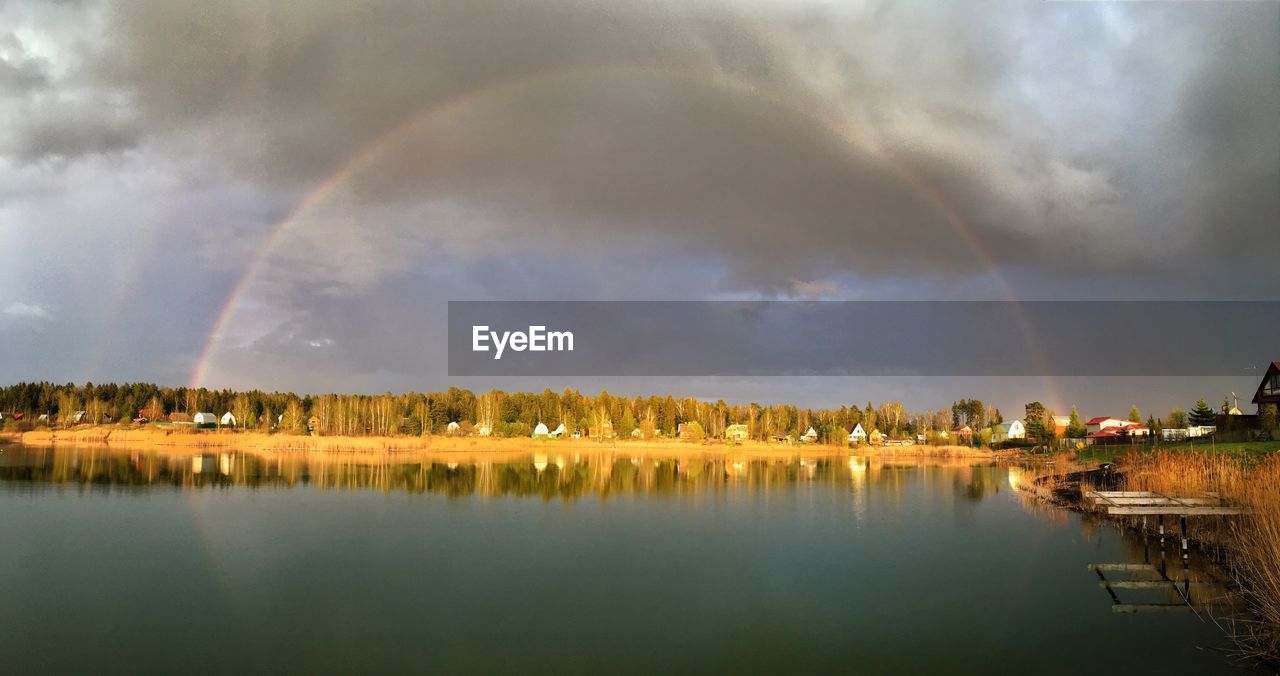 Scenic view of rainbow over lake against sky