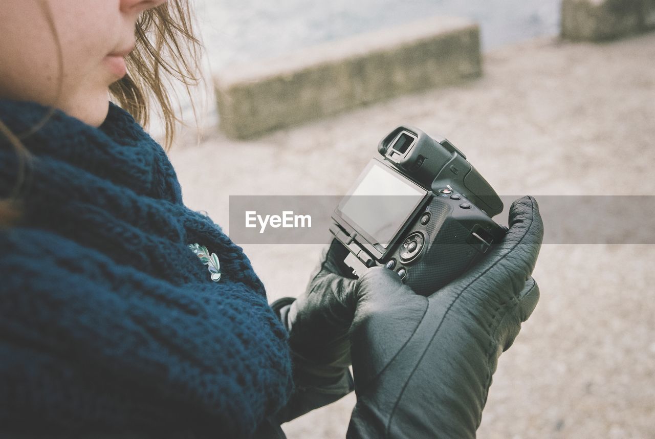 Midsection of woman holding camera outdoors