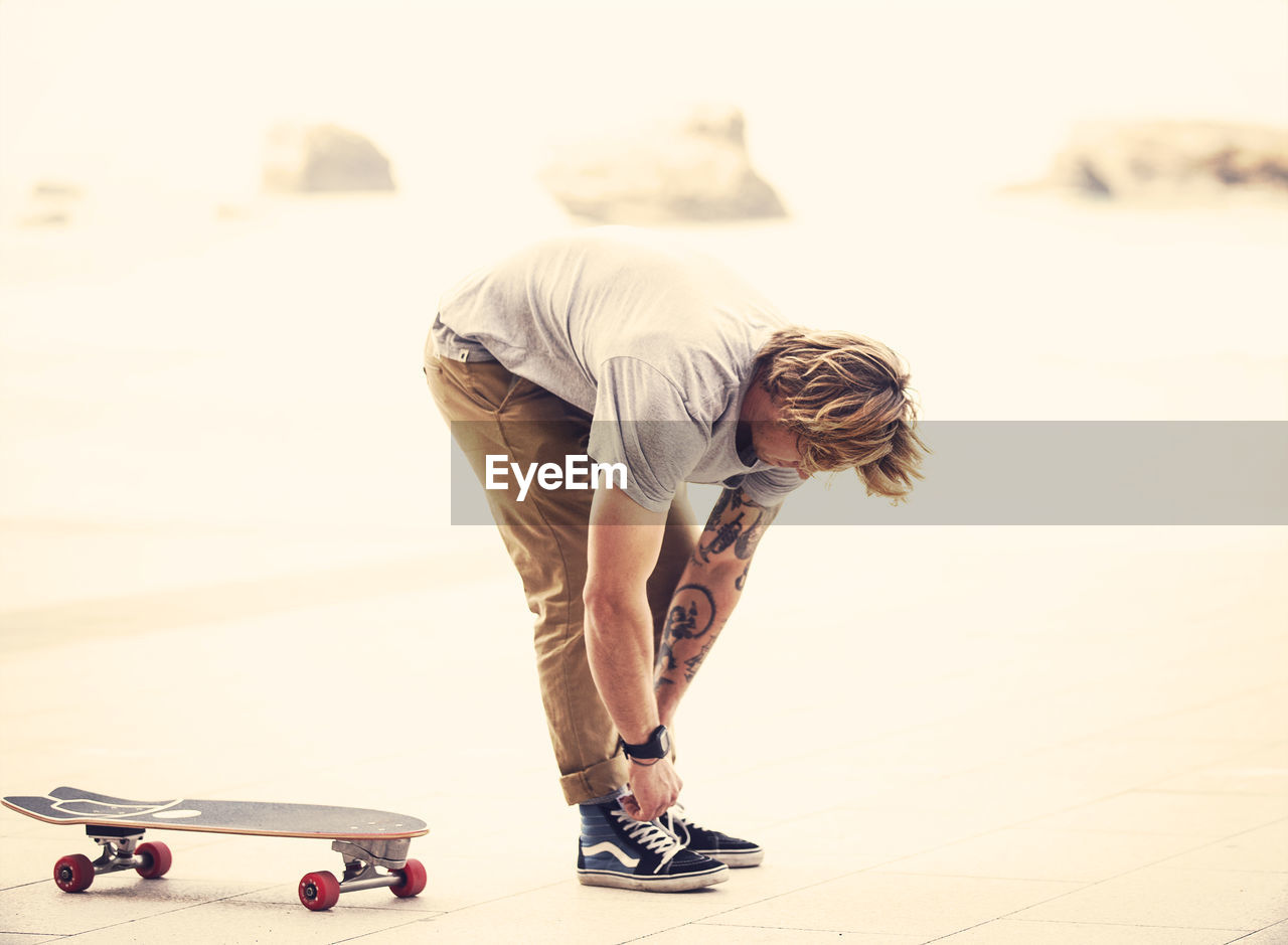 LOW SECTION OF MAN SKATEBOARDING ON SKATEBOARD OUTDOORS