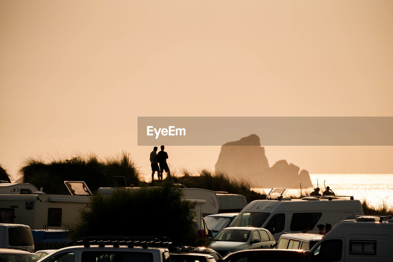 SILHOUETTE PEOPLE BY SEA AGAINST SKY AT SUNSET