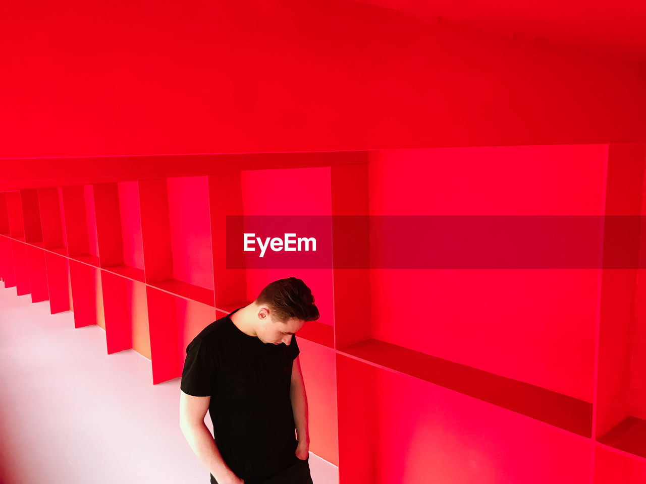 FULL LENGTH OF YOUNG WOMAN LOOKING AWAY AGAINST RED WALL