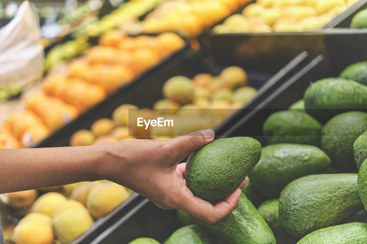 Cropped image of hand holding fruits at market stall