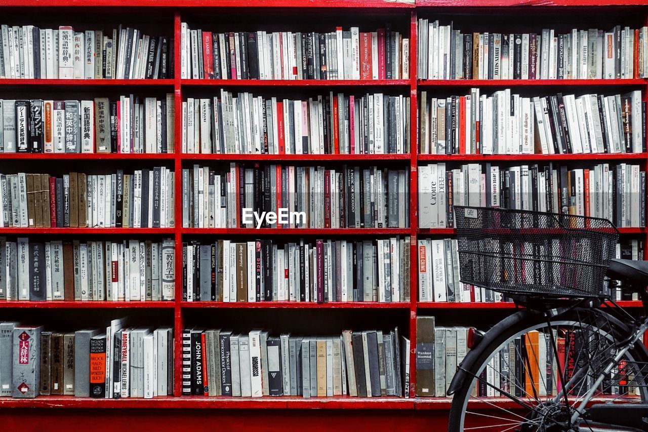 Close-up of bicycle against books in shelf