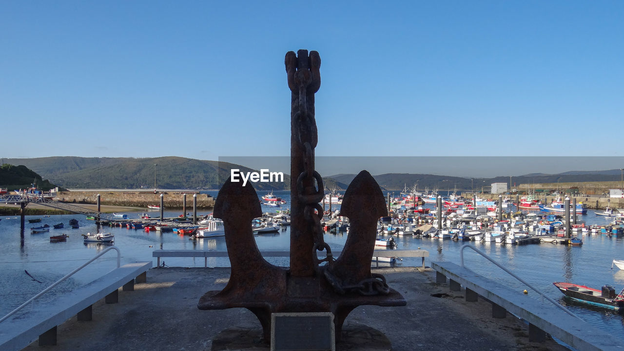 Statue by sea against clear blue sky