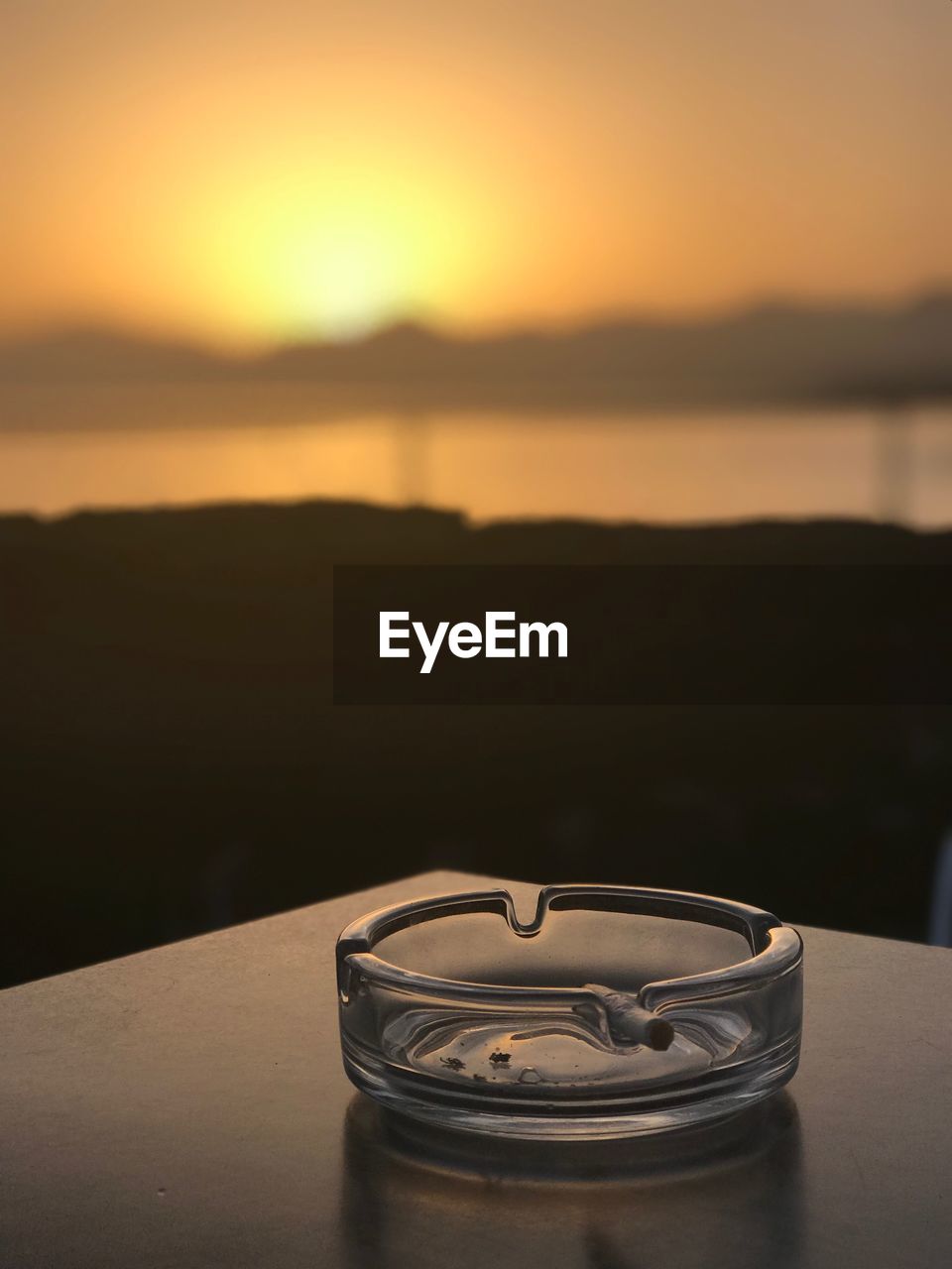 Close-up of ashtray on table at beach against clear sky during sunset