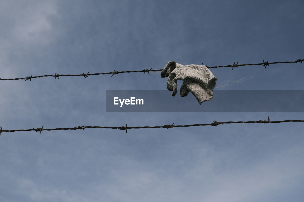 Low angel view of textile on barbed wire against sky