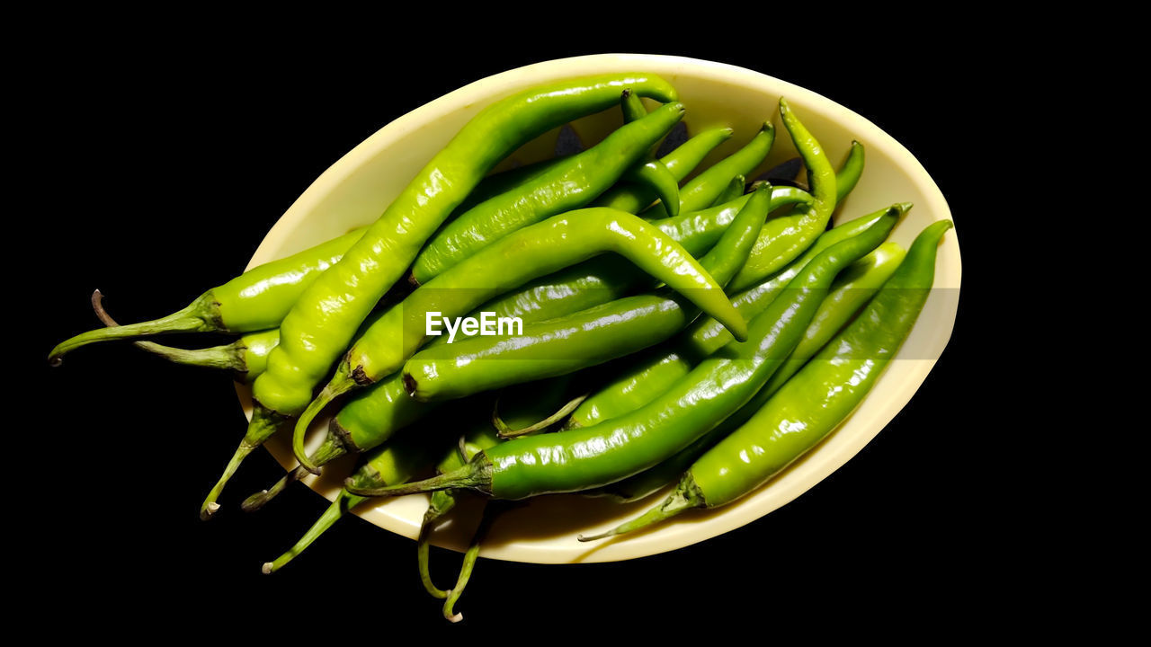 DIRECTLY ABOVE SHOT OF GREEN CHILI PEPPERS AGAINST BLACK BACKGROUND