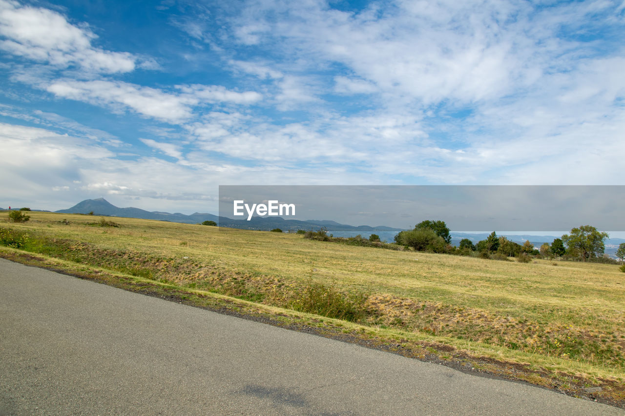 Scenic view of road amidst field against sky