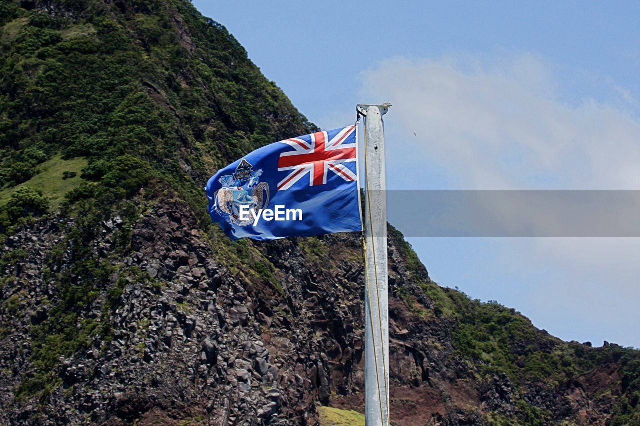 Low angle view of flag waving against mountain