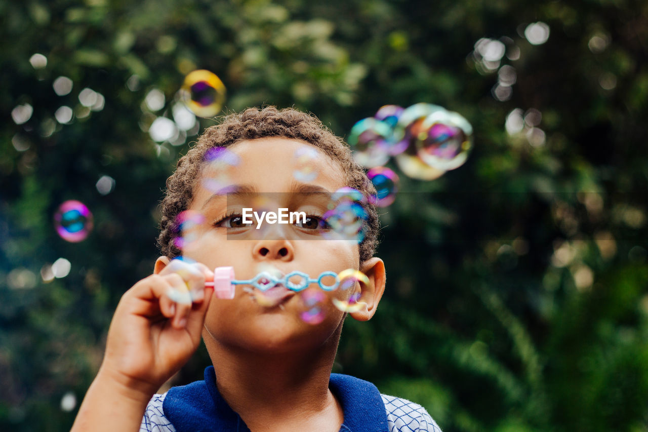 Boy blowing bubbles in park