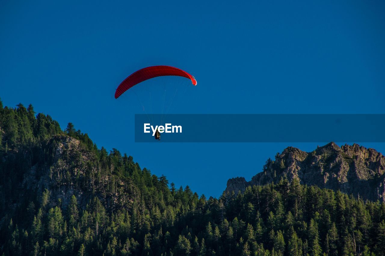 WOMAN PARAGLIDING AGAINST CLEAR BLUE SKY