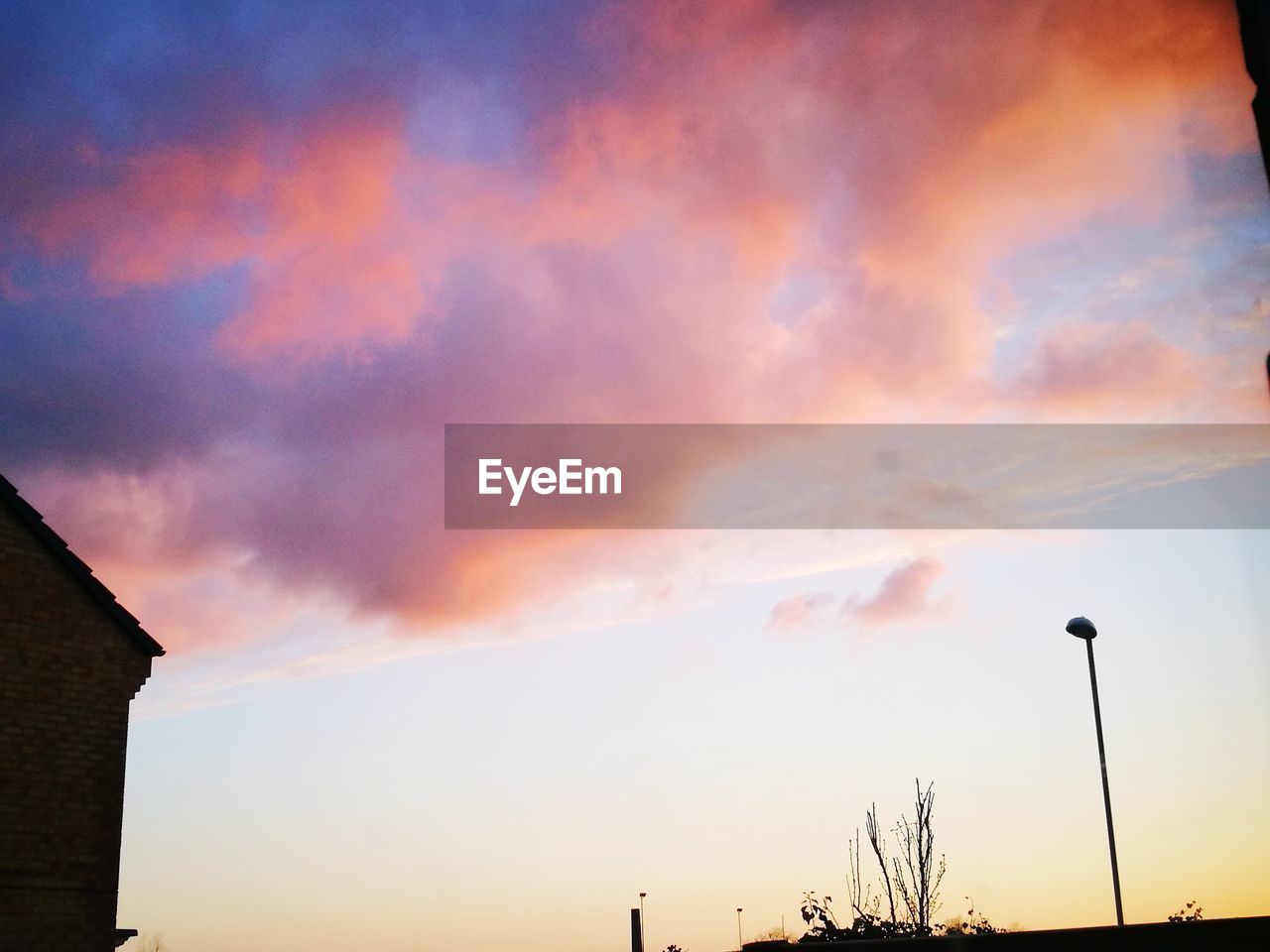 LOW ANGLE VIEW OF STREET LIGHT AGAINST DRAMATIC SKY