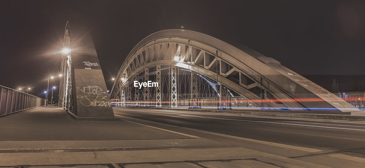 LIGHT TRAILS ON BRIDGE IN CITY AT NIGHT