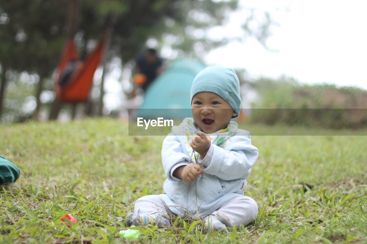 PORTRAIT OF CUTE BOY SITTING ON GRASS