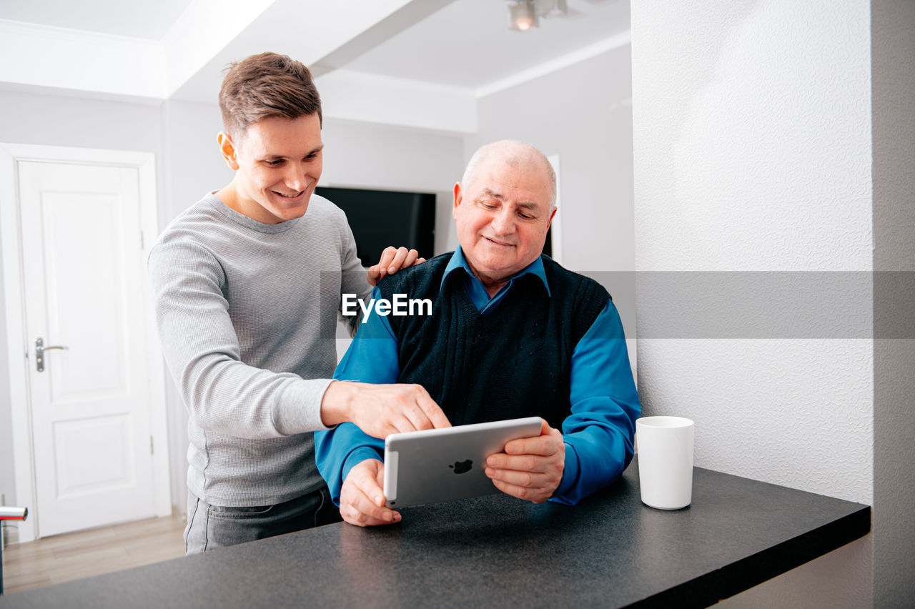 Man using digital tablet by grandfather at home