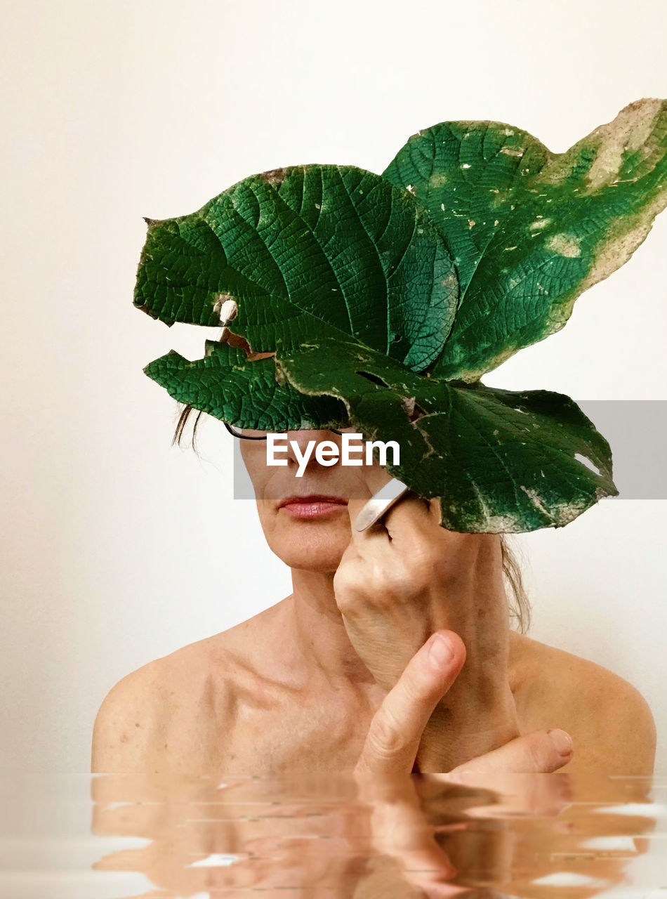 close-up of woman with plant against white background