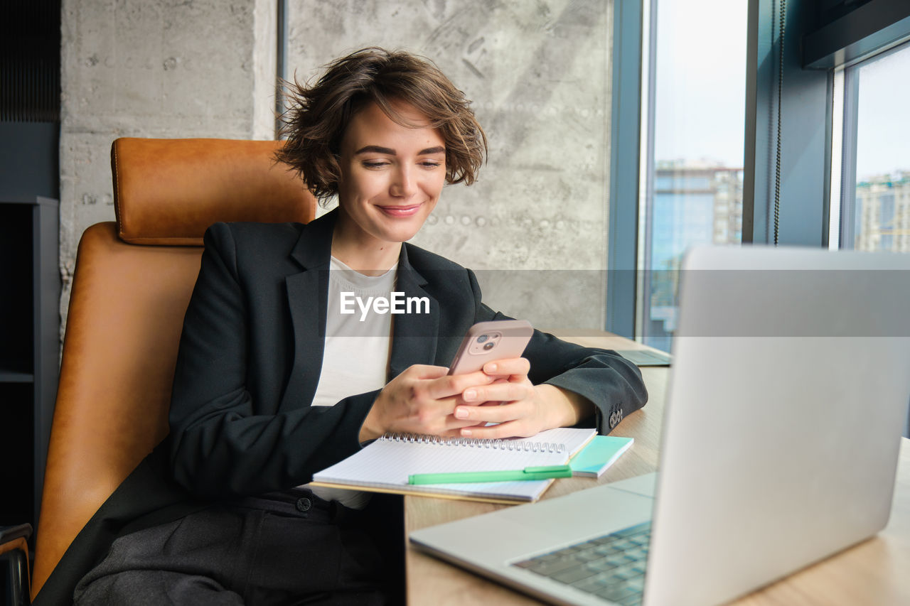 young woman using laptop while sitting on sofa at office