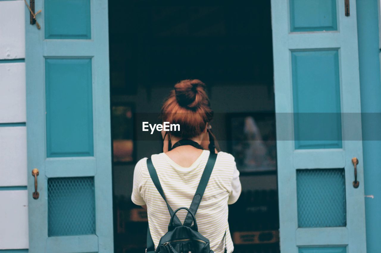 REAR VIEW OF WOMAN STANDING BY BUILDING