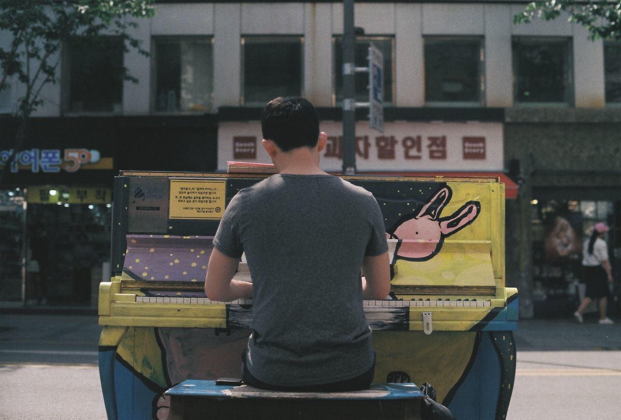 Rear view of street musician playing piano