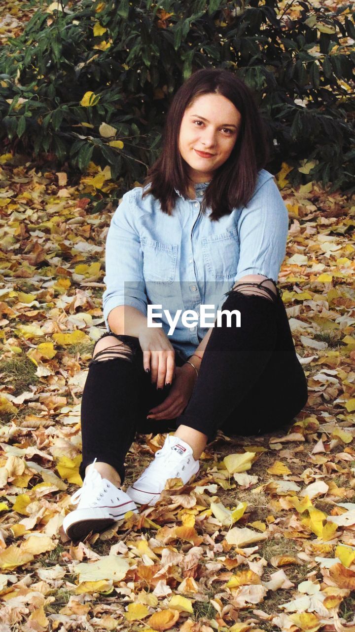 PORTRAIT OF TEENAGE GIRL WEARING AUTUMN LEAVES