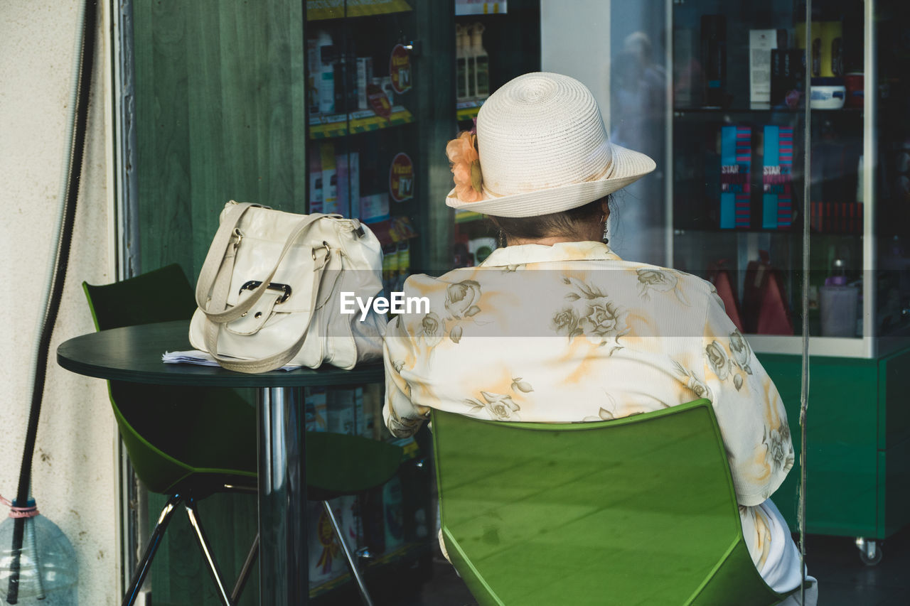 REAR VIEW OF MAN SITTING ON TABLE