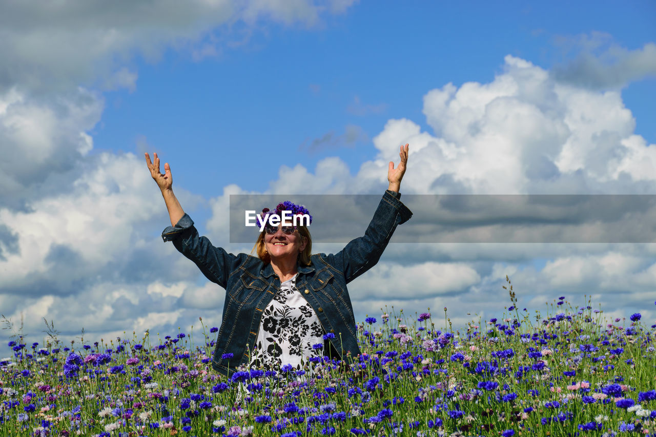 A woman in the middle of a colorful field of cornflowers is happy about summer