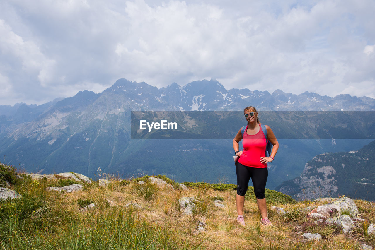 Scenic view of woman standing in front of mountain. woman standing on mountain against sky