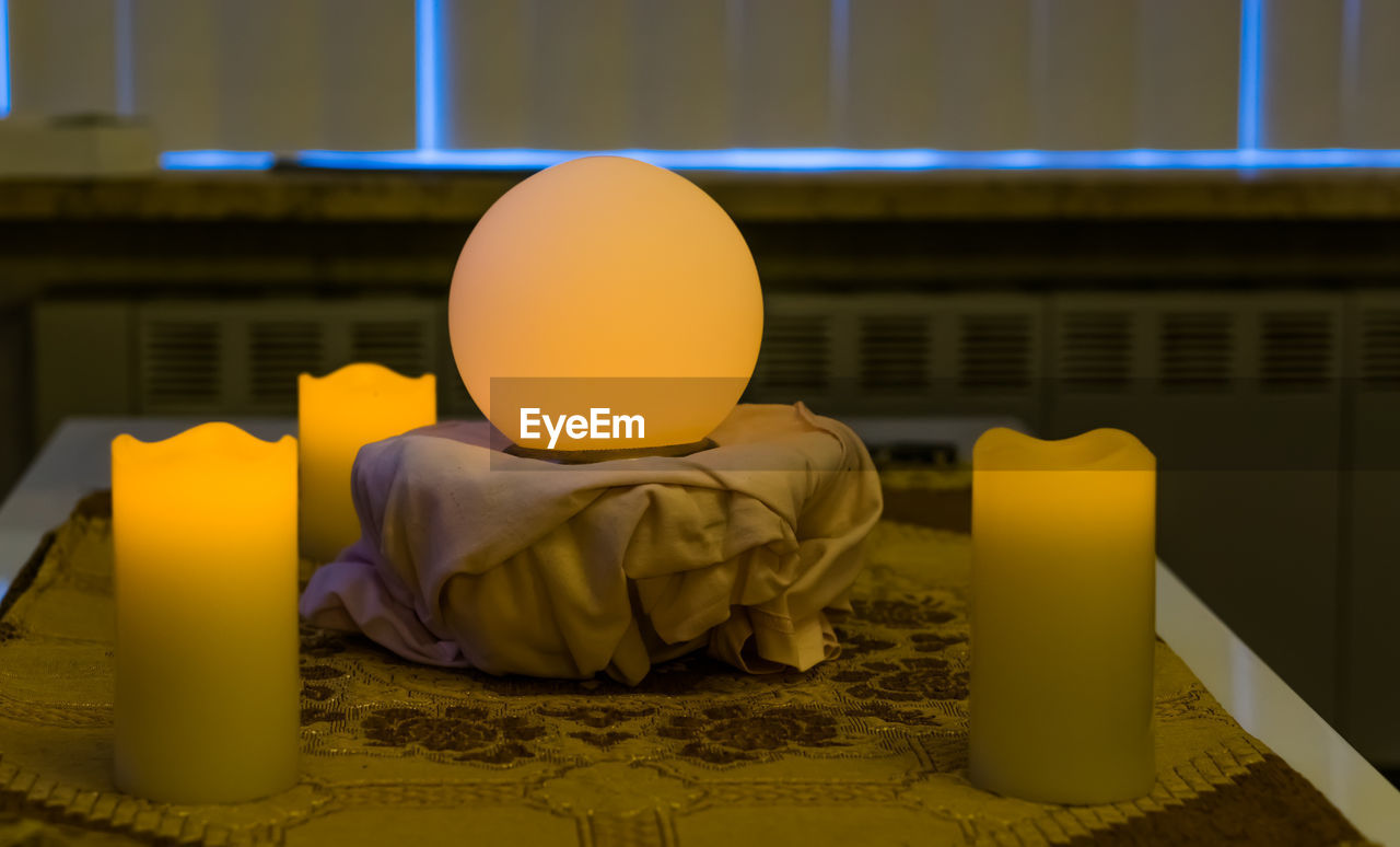 CLOSE-UP OF YELLOW AND LAMP ON TABLE AGAINST BUILDING