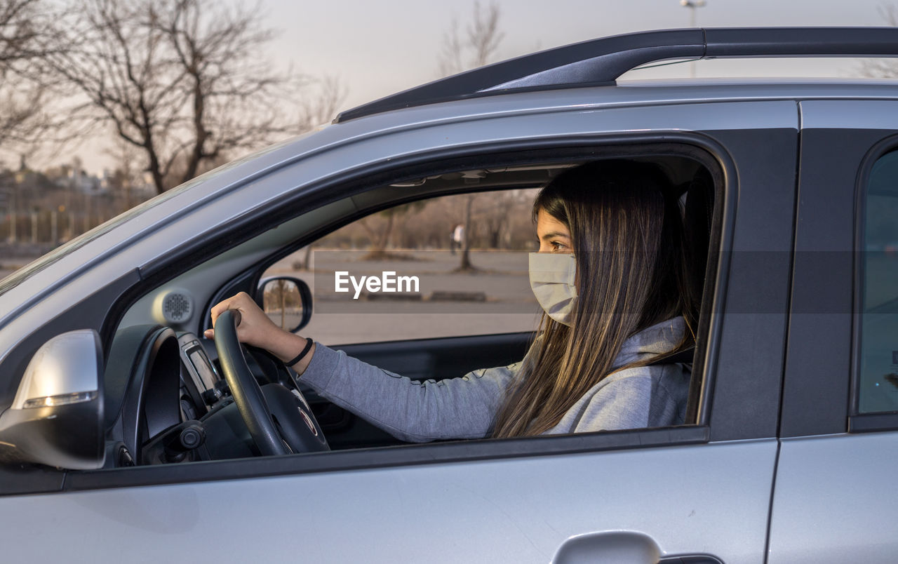 Woman with protective mask driving a car on the road. infection prevent .selective focus.