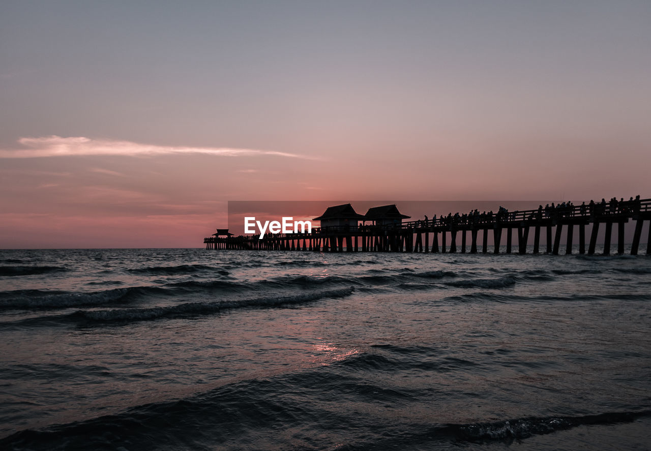 Silhouette pier over sea against sky during sunset