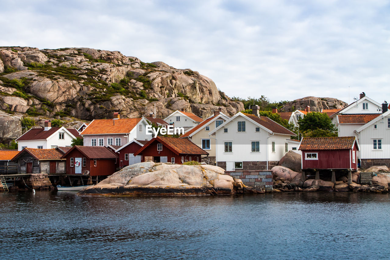 View of town by waterfront against cloudy sky