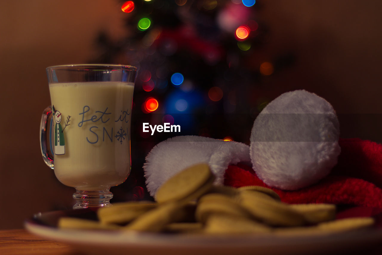 Close-up of drink glass with cookies and christmas decoration on table