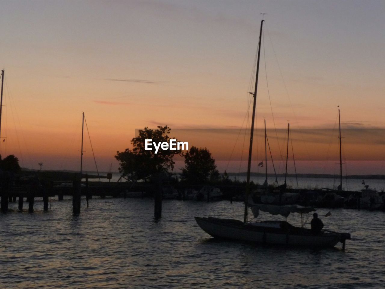 SAILBOATS IN SEA AT SUNSET