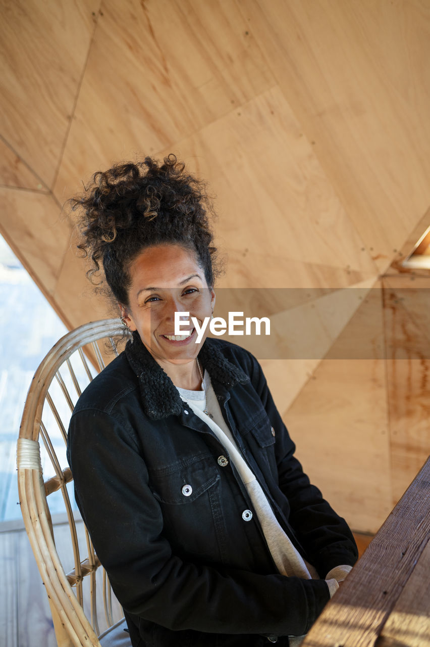 Happy latin woman smiling while sitting indoors.