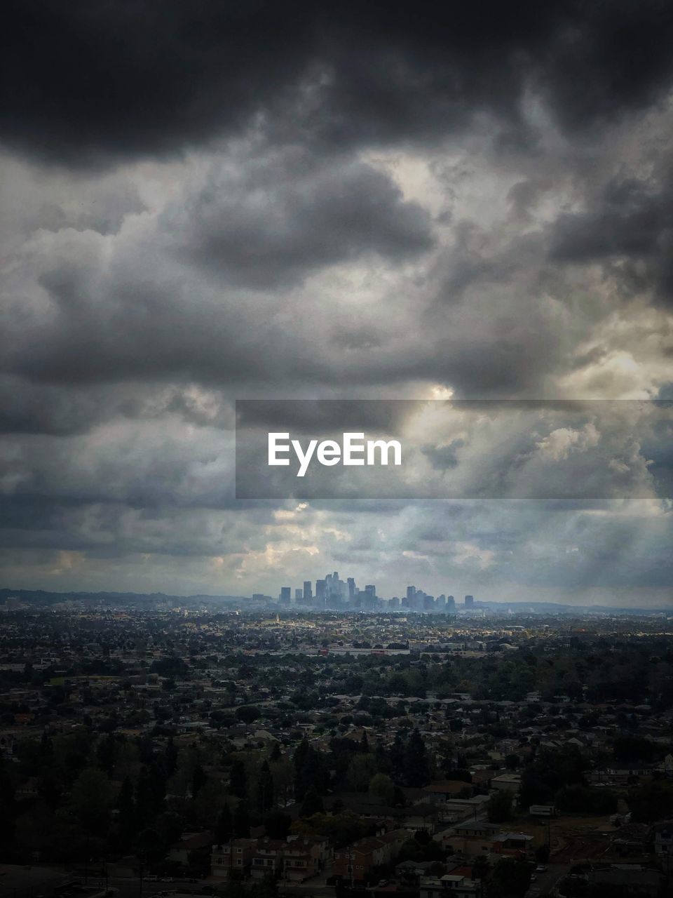 Aerial view of buildings in city against clouds