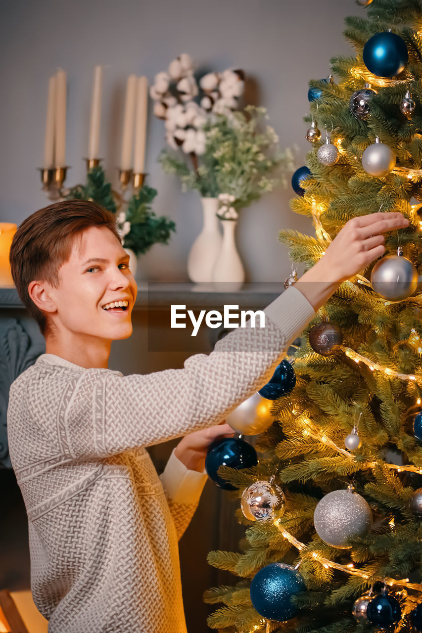 MIDSECTION OF WOMAN WITH CHRISTMAS LIGHTS AT HOME