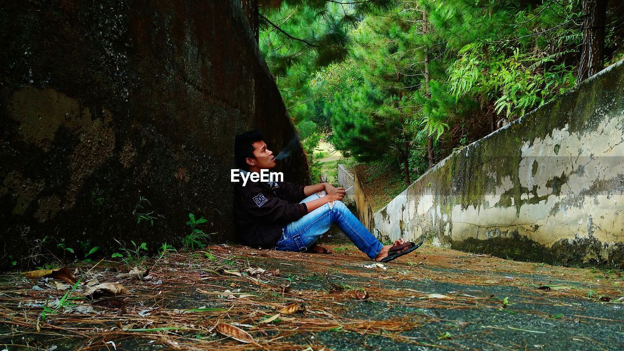 SIDE VIEW OF WOMAN SITTING IN FOREST